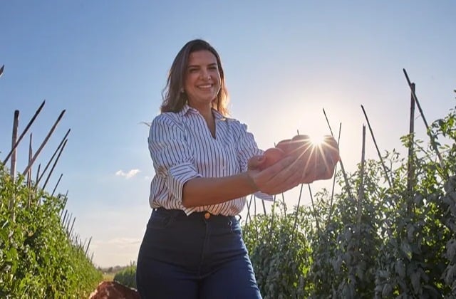 Mulher sorrindo com tomates na mão