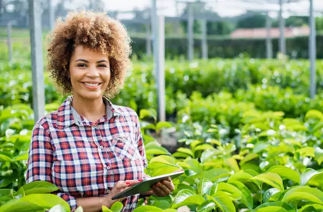 Mulher com tablet na mão em frente à plantação